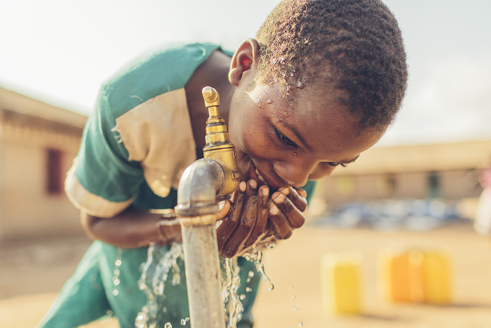 Dina drinks safe water from a Water Mission tap stand at her school.
